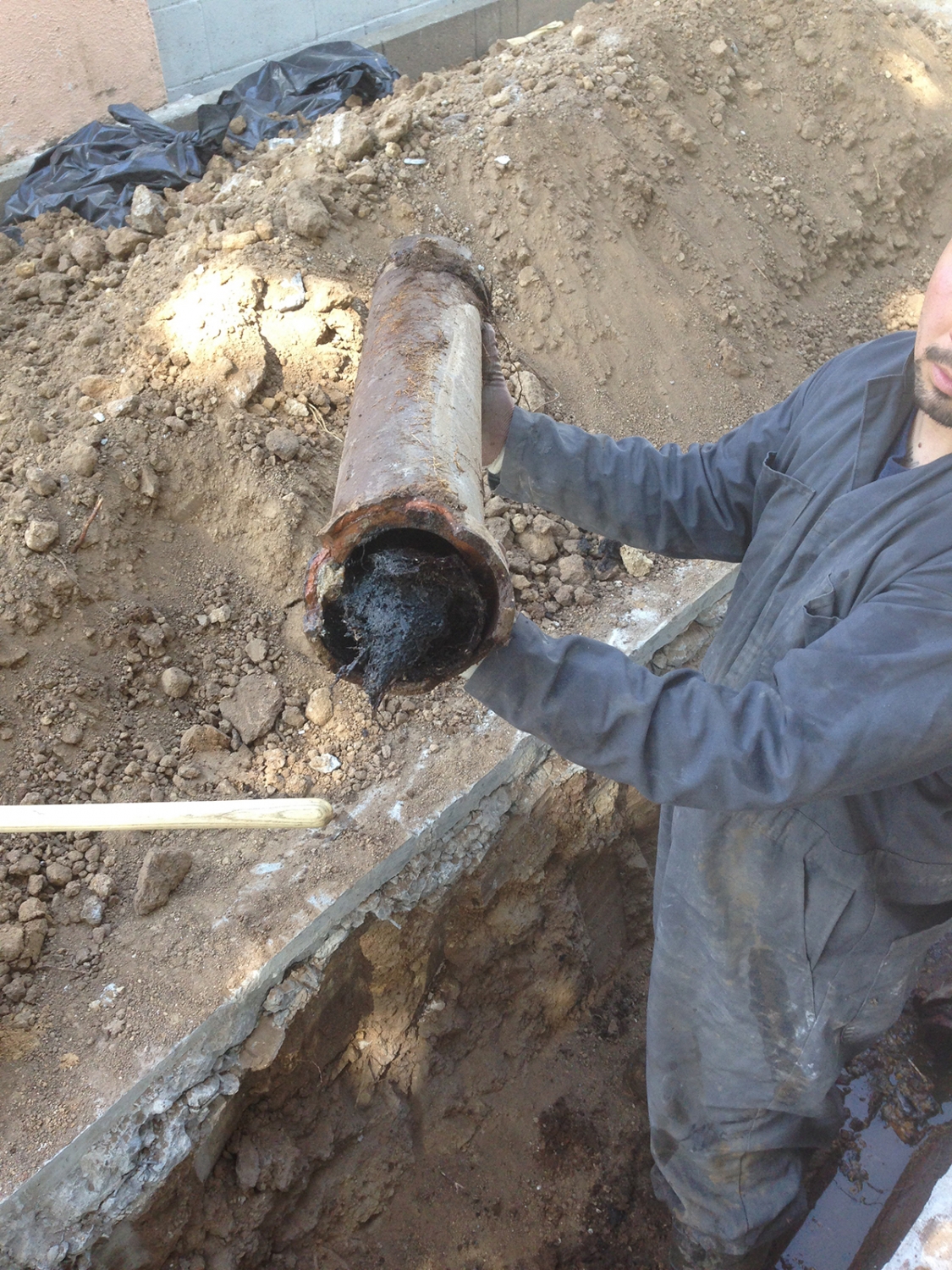 Holding Up A Damaged Main Sewer Line Pipe With Tree Root Intrusion